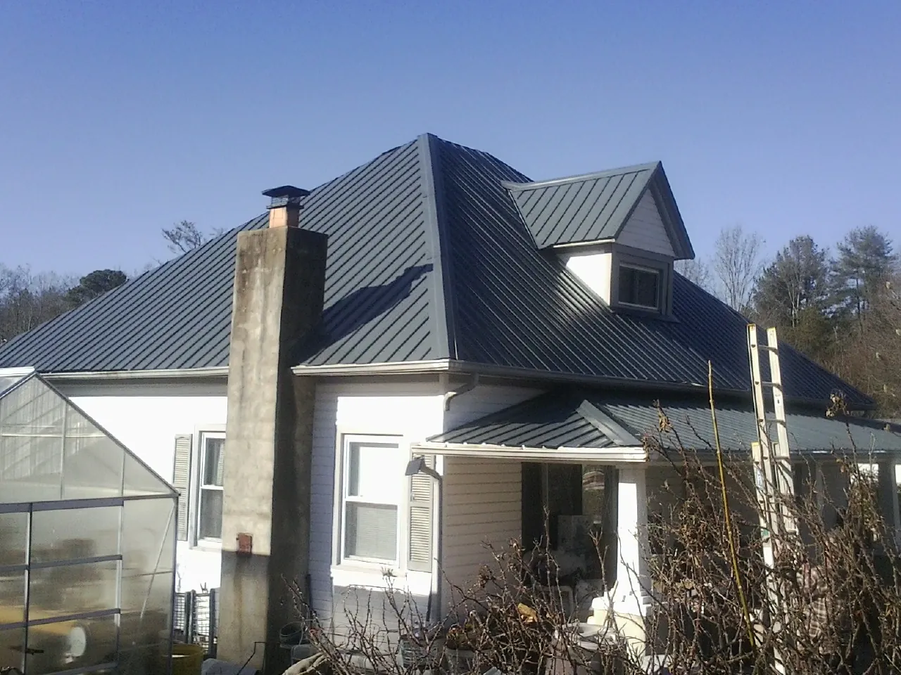Dark blue standing seam metal roof on a white farmhouse with dormer — Slate & Tile Roof Repair by Roofing Brothers in Hibernia