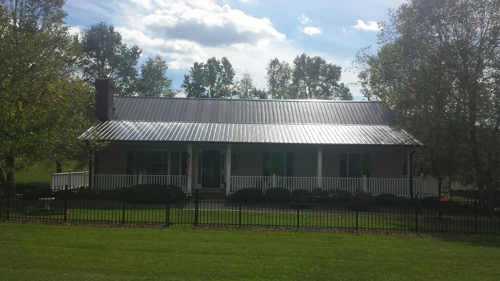 Gray metal roof on a brick ranch with a full width front porch — Gutter Guard Installation work by our crew in Hibernia