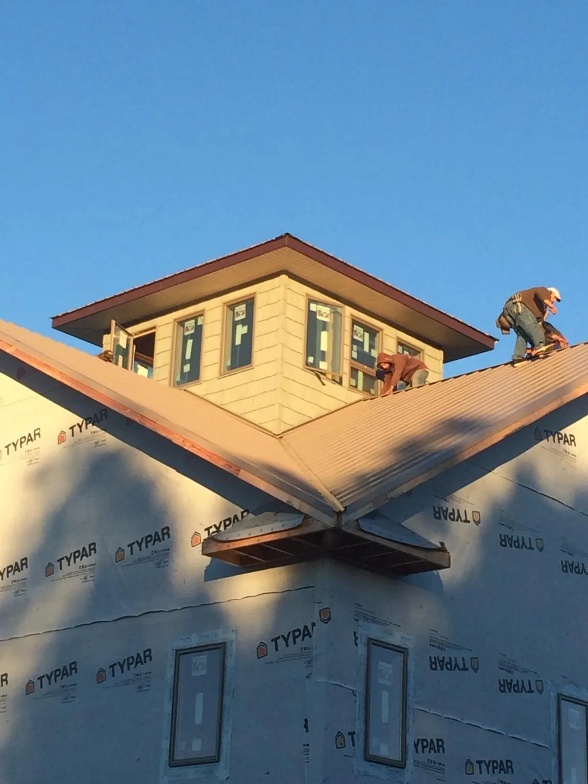 Roofers working around a rooftop cupola on a new metal roof at sunset — Roof Waterproofing in Hibernia by Roofing Brothers